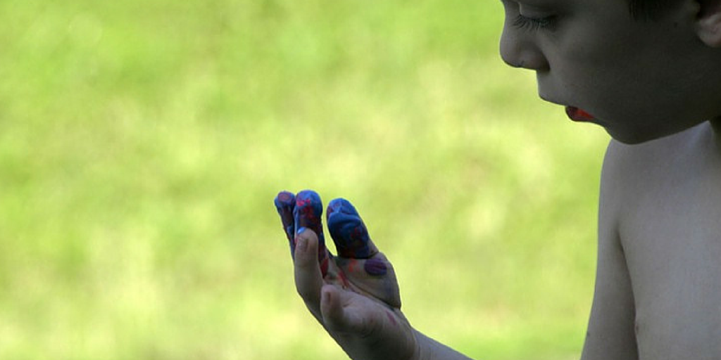 boy looking at red and blue paint on his fingers